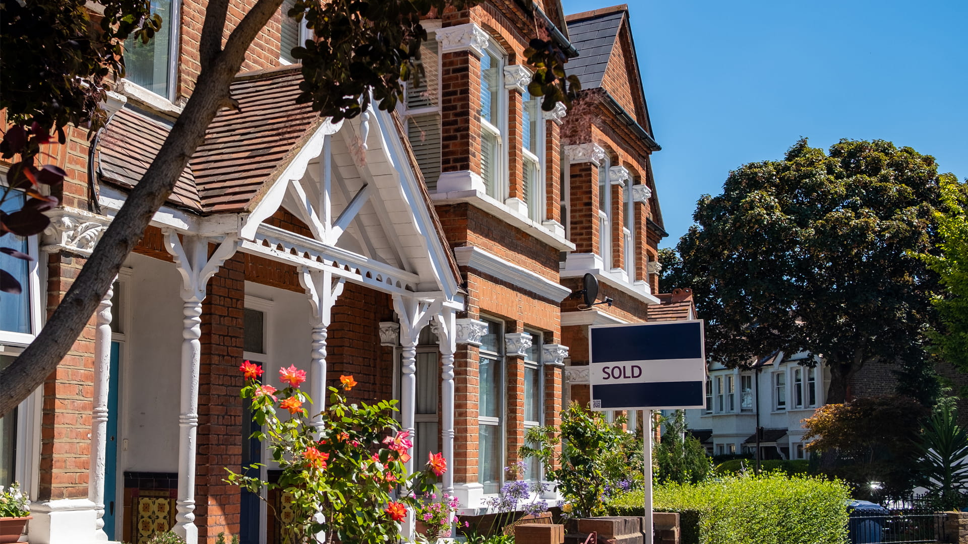 An estate agent's sold sign is displayed outside a victorian terraced house
