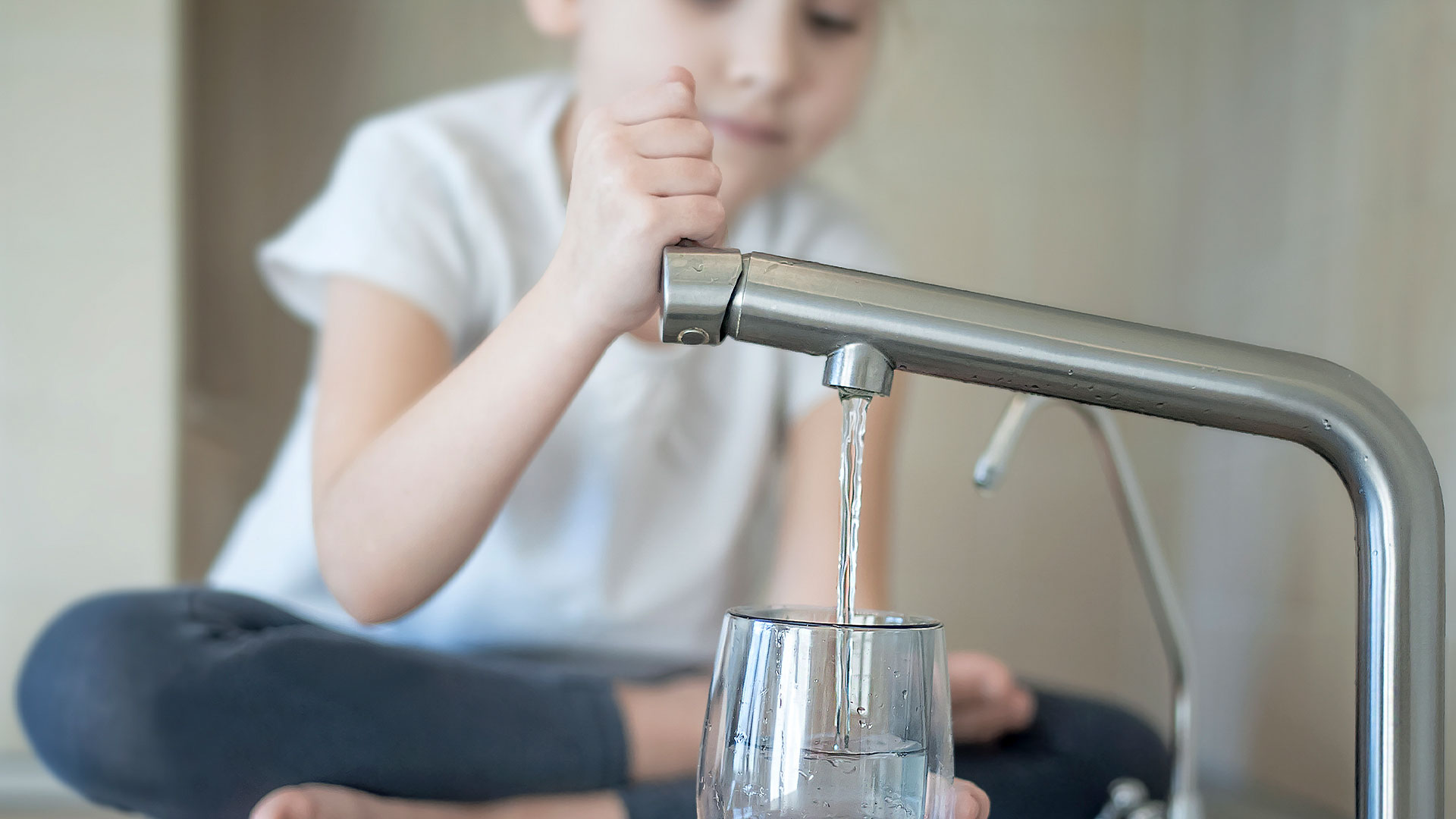 A girl pours drinking water in the glass
